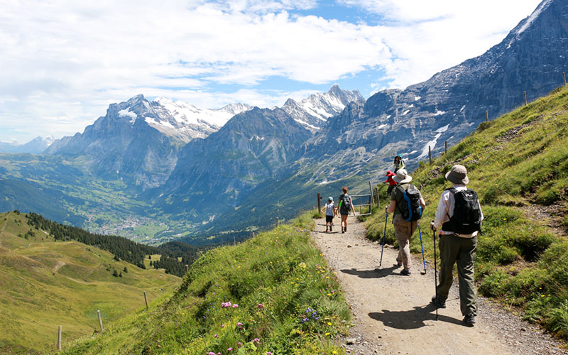 family hiking on trail from Männlichen to Kleine Scheidegg in Jungfrau Region Switzerland with view of Grindelwald